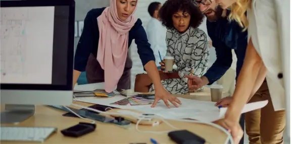 People around papers on a desk People around papers on a desk